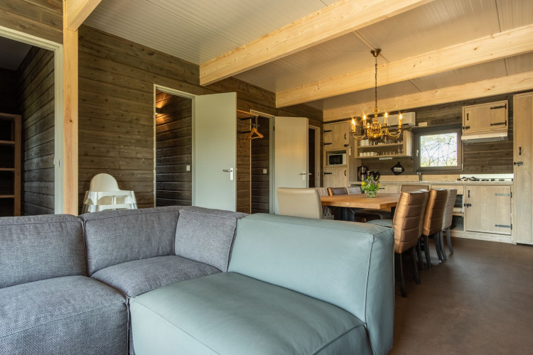 Wohnbereich mit Sofa, Esstisch und Küche in einer Holzhütte im Castle Uylenburght, Kampeerdorp de Zandstuve, Niederlande.
