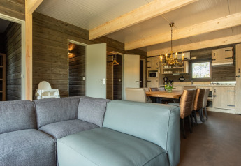 Salon avec canapé, table à manger et cuisine dans un chalet en bois à Castle Uylenburght, Kampeerdorp de Zandstuve, Pays-Bas.