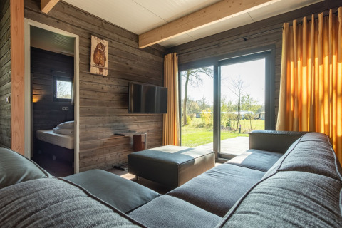 Moderne woonkamer in Castle Uylenburght lodge in Kampeerdorp de Zandstuve met uitzicht op de tuin, Nederland.