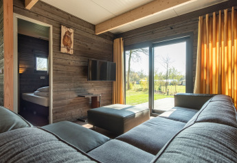 Moderne woonkamer in Castle Uylenburght lodge in Kampeerdorp de Zandstuve met uitzicht op de tuin, Nederland.