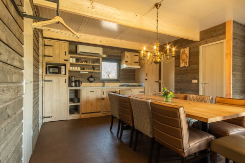 Cozy wooden lodge kitchen with dining table and leather chairs at Castle Uylenburght, Kampeerdorp de Zandstuve, Netherlands.