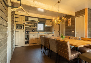 Acogedora cocina de madera con mesa de comedor y sillas de cuero en Castle Uylenburght, Kampeerdorp de Zandstuve, Países Bajos.