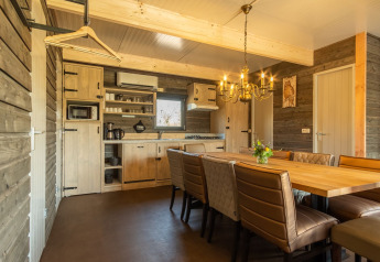 Knusse houten lodgekeuken met eettafel en lederen stoelen in Castle Uylenburght, Kampeerdorp de Zandstuve, Nederland.