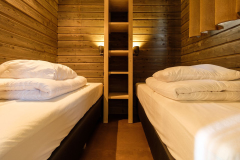 Chambre avec deux lits simples et murs en bois à Castle Uylenburght à Kampeerdorp de Zandstuve, Pays-Bas.