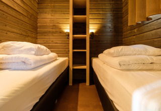 Dormitorio acogedor con paneles de madera y dos camas en Castle Uylenburght en Kampeerdorp de Zandstuve, Países Bajos.