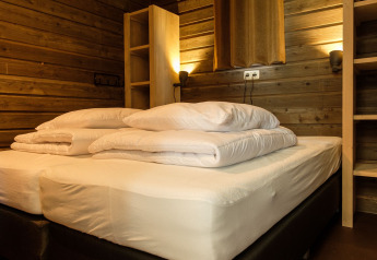Camera da letto accogliente con letti singoli, pareti in legno e luce calda a Castle Uylenburght, Kampeerdorp de Zandstuve.