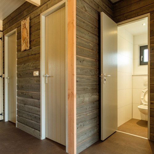 Moderne Toiletten mit grauen Holzverkleidungen und offenen Türen bei Castle Uylenburght, De Zandstuve.