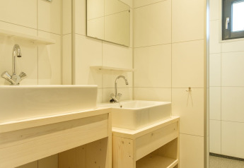 Modernes Badezimmer mit zwei weißen Waschbecken, Holzunterschränken und Spiegeln an der Wand.