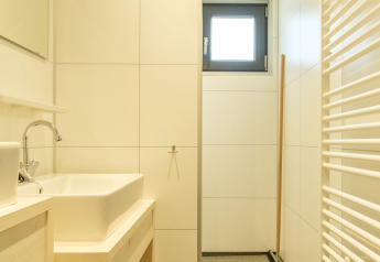 Modernes Badezimmer mit Fliesenwänden, Fenster, Waschbecken und Regal im Castle Uylenburght, Niederlande.