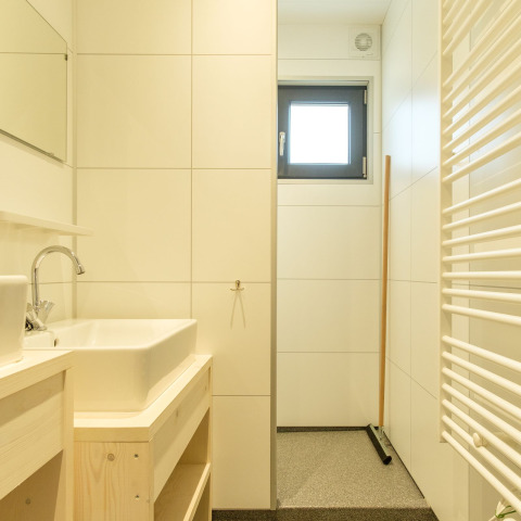 Modern bathroom with tiled walls, window, sink, and storage shelf in Castle Uylenburght, Netherlands.