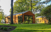 Wellness Lodge ved De Hooge Veluwe, Holland, omgivet af grønne træer og græsplæne på en solrig dag.