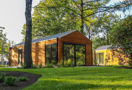 Wellness Lodge a De Hooge Veluwe, Paesi Bassi, circondata da alberi e prato verde in una giornata di sole.