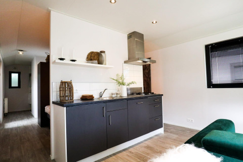 Moderne kitchenette in Wellness Lodge bij De Hooge Veluwe, Nederland, met stijlvolle donkere kasten.
