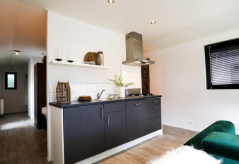 Moderne kitchenette in Wellness Lodge bij De Hooge Veluwe, Nederland, met stijlvolle donkere kasten.