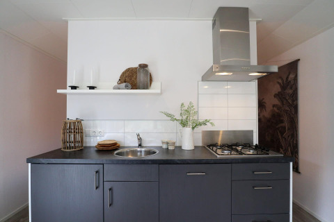 Cucina moderna nel Wellness Lodge a De Hooge Veluwe, Paesi Bassi, con mobili scuri e piano cottura.