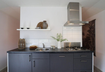 Cucina moderna nel Wellness Lodge a De Hooge Veluwe, Paesi Bassi, con mobili scuri e piano cottura.