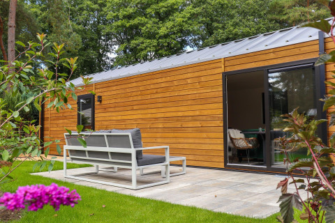 Moderne houten lodge met zithoek en tuin bij Wellness Lodge in De Hooge Veluwe, Nederland.