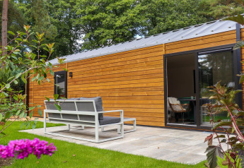 Moderne houten lodge met terras en tuin bij Wellness Lodge, De Hooge Veluwe, Nederland.