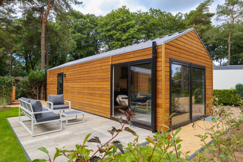 Buitenaanzicht van de Wellness Lodge bij De Hooge Veluwe in Nederland, met terras en tuingroen.