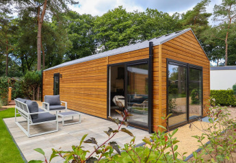 Vista esterna della Wellness Lodge a De Hooge Veluwe nei Paesi Bassi, con terrazza e giardino.