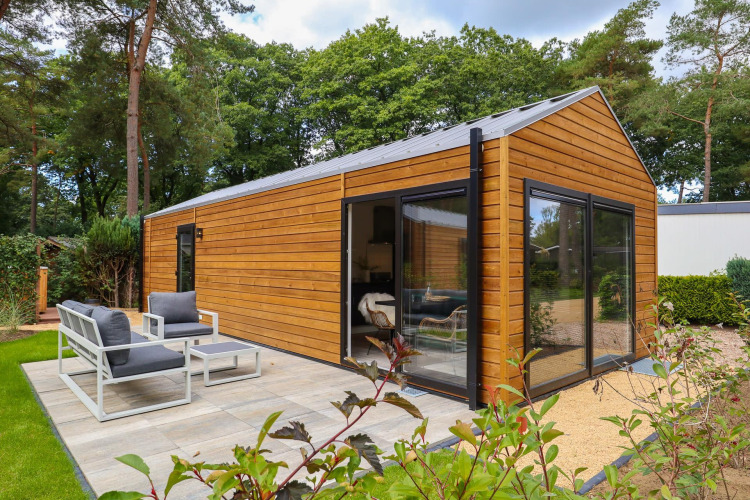 Exterior view of Wellness Lodge at De Hooge Veluwe in the Netherlands, with patio and garden setting.