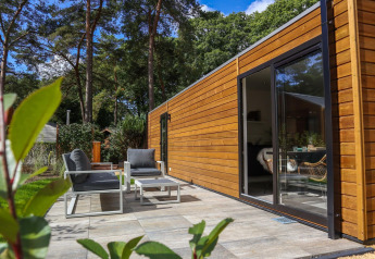 Patio esterno e cabina moderna in legno al Wellness Lodge di De Hooge Veluwe, Paesi Bassi, vista foresta.