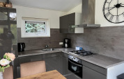 Moderne keuken in lodge L-Pavilion 6 te De Achterhoek, Nederland, met grijze kasten en grote wandklok.