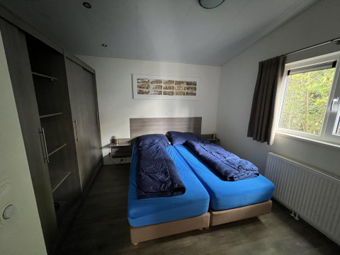 Dormitorio en L-Pavilion 6, De Achterhoek, Países Bajos, con dos camas individuales, sábanas azules y ventana.