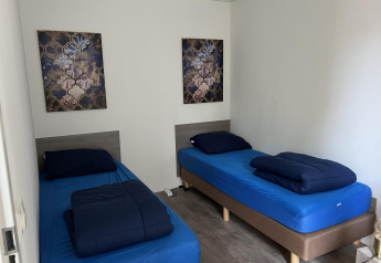 Foto eines Zimmers mit zwei Einzelbetten, blauer Bettwäsche und moderner Kunst im L-Pavilion 6 in De Achterhoek.