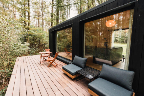 Buiten houten terras bij Koya Tiny Cabin in Wilsumer Berge, Duitsland, omringd door bosrijke natuur.