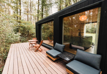 Terrasse extérieure en bois du Koya Tiny Cabin à Wilsumer Berge, Allemagne, entourée de forêt dense.