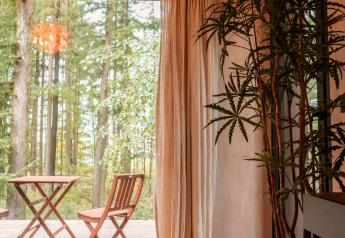 Intérieur du Koya Tiny Cabin à Wilsumer Berge, Allemagne, vue forêt et mobilier terrasse en bois.