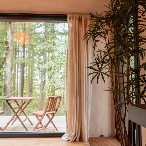 Interior de la Koya Tiny Cabin en Wilsumer Berge, Alemania, con vistas al bosque y terraza amueblada.