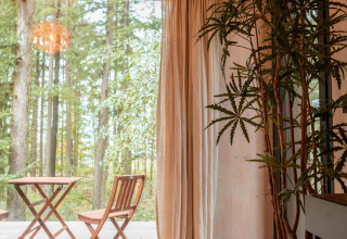 Interior de la Koya Tiny Cabin en Wilsumer Berge, Alemania, con vistas al bosque y terraza amueblada.