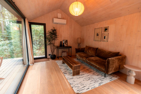 Knusse woonkamer in Koya Tiny Cabin bij Wilsumer Berge in Duitsland met zetel en grote glaspartijen