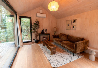 Acogedora sala de estar en Koya Tiny Cabin en Wilsumer Berge, Alemania, con sofá y grandes ventanales