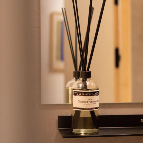 Glass bottle with fragrance sticks on a shelf in front of a mirror at Koya Tiny Cabin, Wilsumer Berge, Germany.