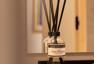 Glass bottle with fragrance sticks on a shelf in front of a mirror at Koya Tiny Cabin, Wilsumer Berge, Germany.