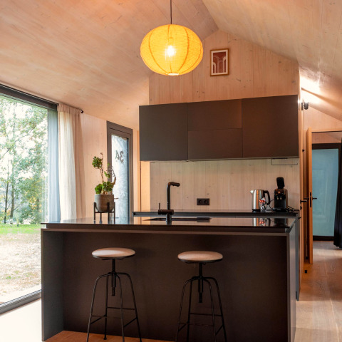 Moderne keuken met een eiland en krukken in Koya Tiny Cabin aan Wilsumer Berge, Duitsland.