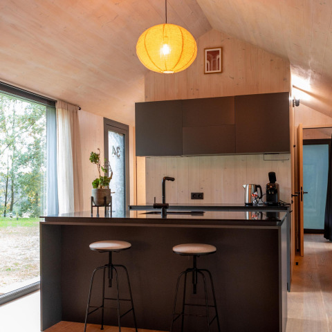 Moderne keuken met een eiland en krukken in Koya Tiny Cabin aan Wilsumer Berge, Duitsland.