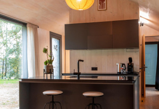 Isla de cocina moderna con taburetes en Koya Tiny Cabin en Wilsumer Berge, Alemania, diseño minimalista.