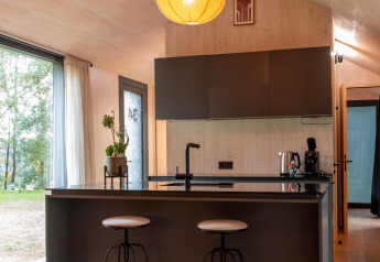 Moderne Küchenzeile mit Barhockern im Koya Tiny Cabin, Wilsumer Berge, Deutschland, mit Holzdekor.
