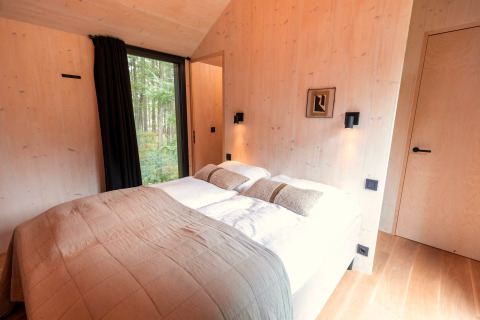 Slaapkamer in Koya Tiny Cabin bij Wilsumer Berge, Duitsland, met een tweepersoonsbed en boszicht.