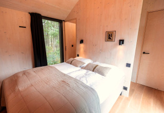 Slaapkamer in Koya Tiny Cabin bij Wilsumer Berge, Duitsland, met een tweepersoonsbed en boszicht.