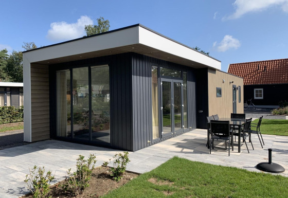 Moderne Lodge Pavilion 6 in De Achterhoek, Niederlande. Terrasse mit Gartenmöbeln, sonniges Wetter.