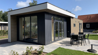 Moderne Lodge Pavilion 6 in De Achterhoek, Niederlande. Terrasse mit Gartenmöbeln, sonniges Wetter.