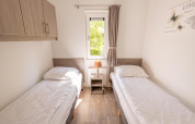 Luminoso dormitorio doble con dos camas individuales, ventana y lámpara en Pavilion 6 en De Achterhoek, Holanda.