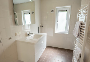 Moderne, lichte badkamer in Pavilion 6, De Achterhoek, Nederland, met wastafel, spiegel en raam.
