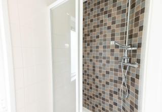 Ducha moderna en el Pavilion 6 de De Achterhoek, Países Bajos, con azulejos marrones y puerta de cristal.