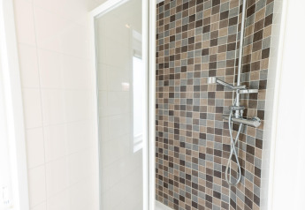 Moderne douche in Pavilion 6 op De Achterhoek, Nederland, met bruine mozaïektegels en glazen deur.